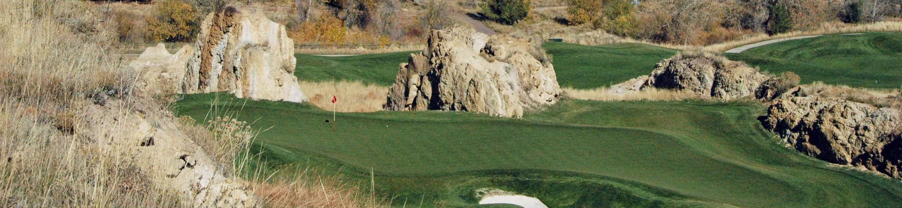 Sandstone fins and a green with a red flagstick at Fossil Trace Golf Course in Golden, Colorado.